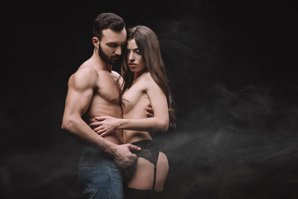 sexual boyfriend hugging nude girlfriend, isolated on black with smoke