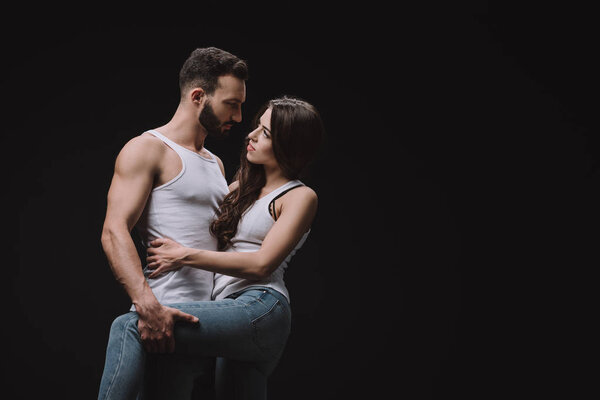 Красивый мужчина обнимает женщину в белом сингле изолированный на черном
