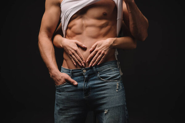 обрезанный вид девушки, обнимающей сексуального мужчину, изолированного от черного
