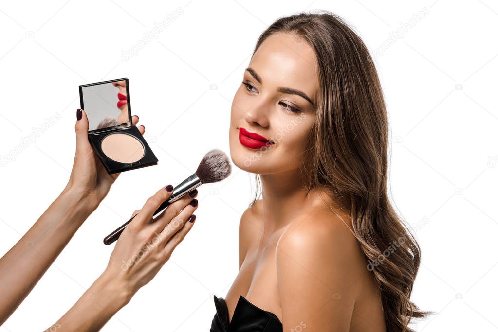 cropped view of woman applying powder with cosmetic brush on face of attractive girl isolated on white