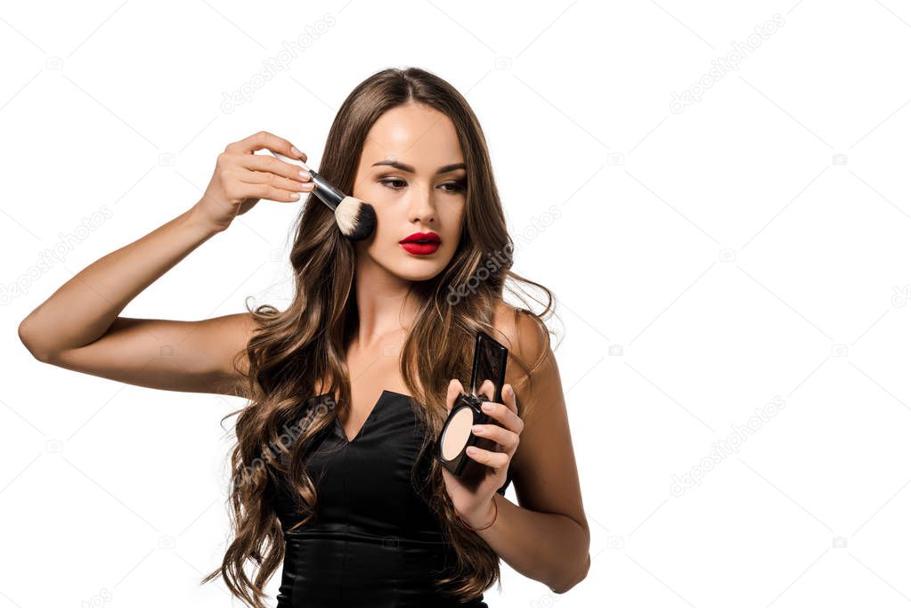 attractive girl in black dress applying powder on face with cosmetic brush isolated on white