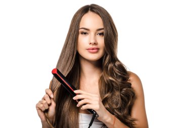 beautiful girl with long brown hair using straightener and looking at camera isolated on white clipart