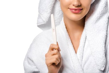 Kız bornoz gülümseyen ve gösteren hamilelik testi üzerinde beyaz izole kırpılmış görünümünü