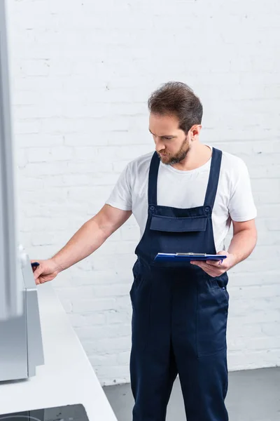 Homem Manual Adulto Focado Com Prancheta Verificando Forno Microondas Cozinha — Fotografia de Stock