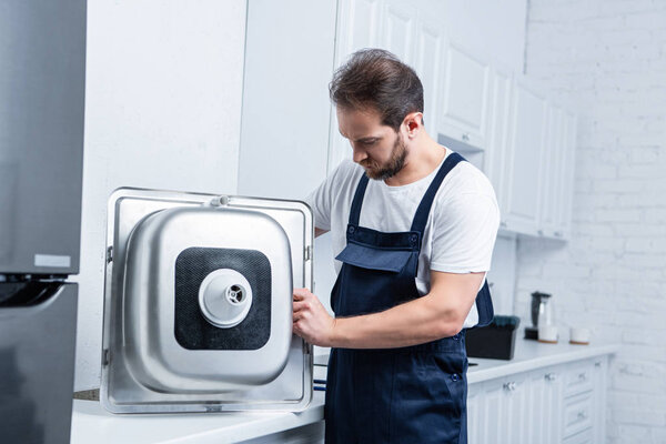 селективный фокус бородатого ремонтника в работе в целом ремонт раковины на кухне
 