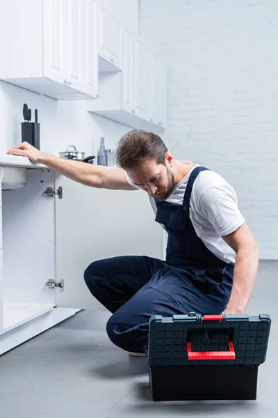 英俊的成人修理工与工具箱检查水槽在厨房 — 图库照片