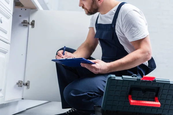 Partial View Repairman Working Overall Writing Clipboard Checking Sink Kitchen — Stock Photo, Image