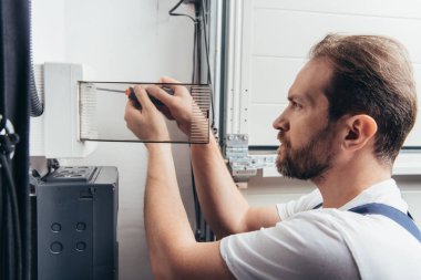 focused adult male electrician repairing electrical box by screwdriver  clipart