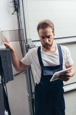Erkek sakallı tamircisi elektrik kutusunu kontrol dijital tablet ile odaklı 