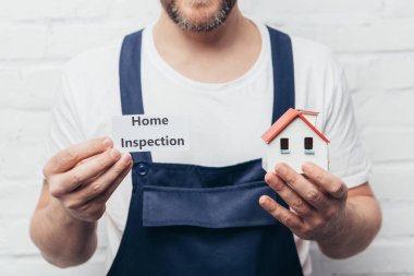 cropped image of male craftsman showing house model and card with lettering home inspection  clipart