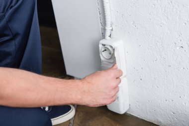 partial view of male electrician checking plug socket  clipart