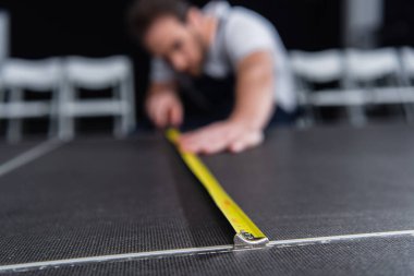 selective focus of male craftsman making measurements of floor by measuring tape clipart
