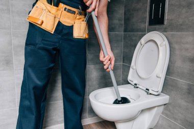 partial view of male plumber using plunger and cleaning toilet in bathroom  clipart