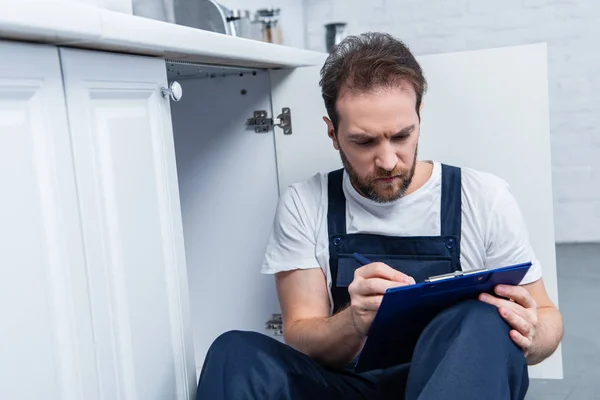 Serious Adult Craftsman Writing Clipboard While Sitting Floor Kitchen — Stock Photo, Image