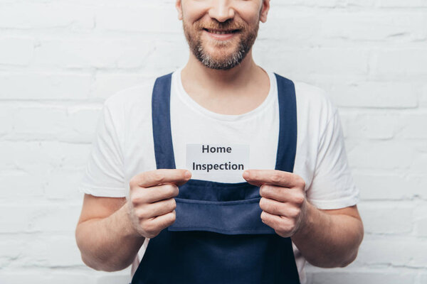 partial view of male craftsman showing card with lettering home inspection 