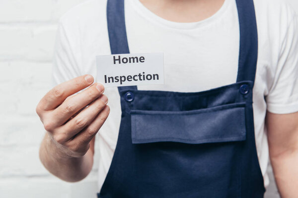 cropped image of male craftsman showing card with lettering home inspection 