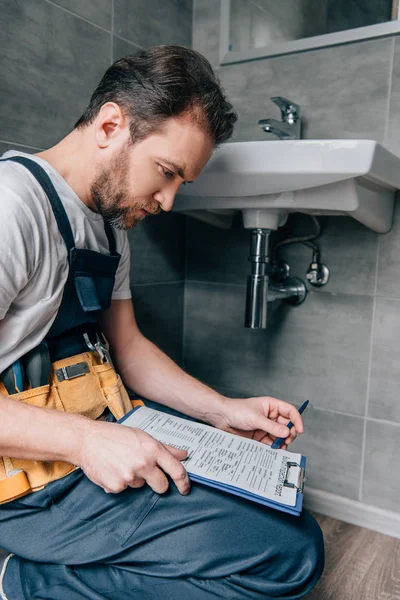 Gebaarde Mannelijke Loodgieter Met Toolbelt Schrijven Klembord Buurt Van Gebroken — Stockfoto