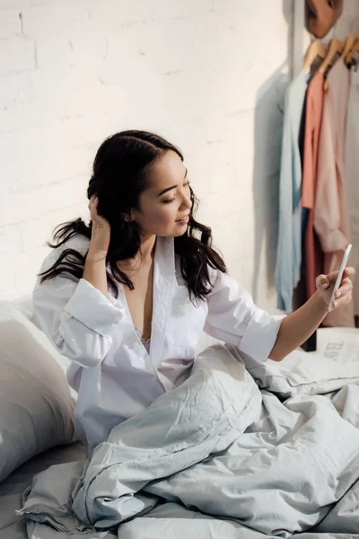 Piękna Uśmiechnięta Dziewczyna Azjatyckich Biorąc Selfie Smartphone Łóżku — Zdjęcie stockowe