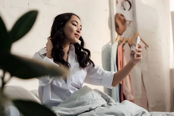 Vacker Ung Kvinna Vit Skjorta Tar Selfie Med Smartphone Sängen — Stockfoto