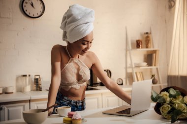 dantel bralette ve evde kahvaltı sırasında dizüstü kullanarak kafa havluya gülümseyen güzel genç kadın 