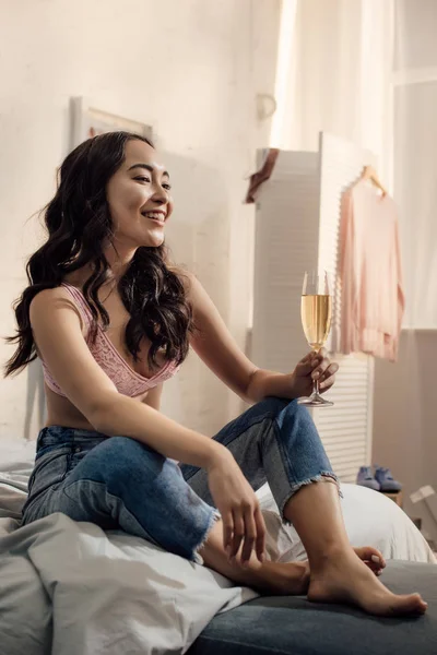 幸せの魅力的なアジアの女性はワインのガラスを保持していると ベッドの上に座って — ストック写真