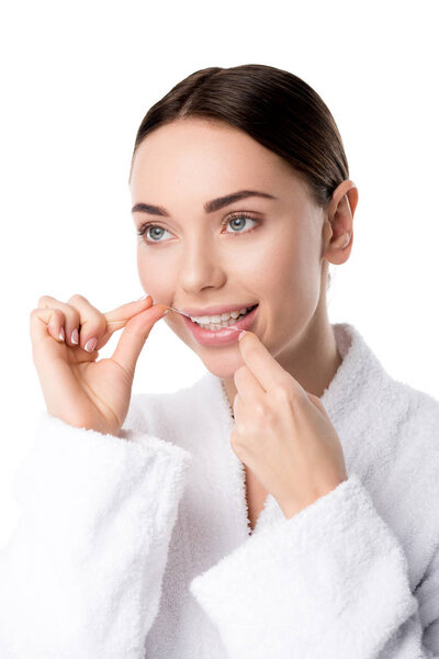beautiful woman in white bathrobe flossing teeth isolated on white