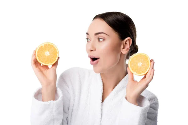 Verrast Vrouw Witte Badjas Holding Sinaasappelen Geïsoleerd Wit — Stockfoto