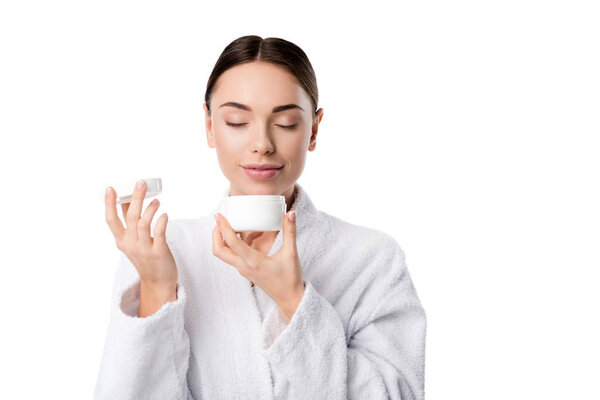 woman in bathrobe with eyes closed smelling aroma of face cream isolated on white