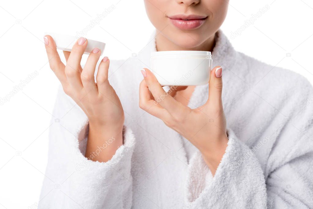 cropped view of woman in bathrobe smelling aroma of face cream isolated on white