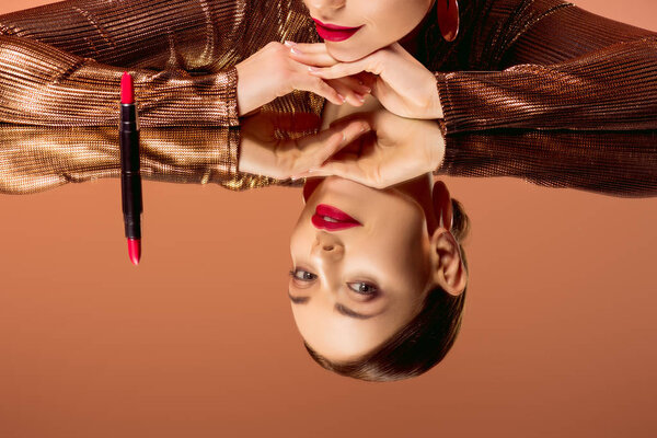 partial view of beautiful woman with glamorous makeup, red lipstick and mirror reflection isolated on orange