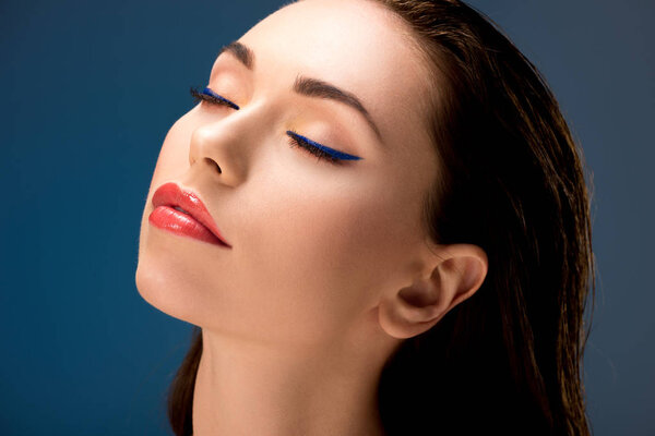 portrait of beautiful woman with glamorous makeup and eyes closed isolated on blue