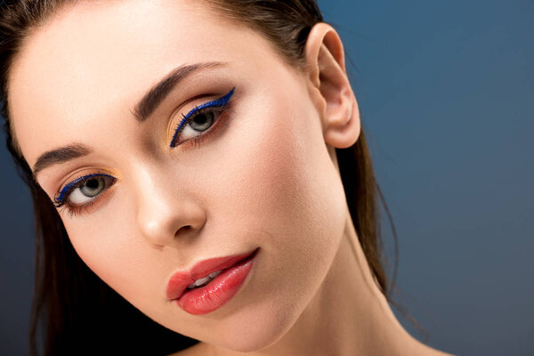 portrait of beautiful woman with glamorous makeup looking at camera isolated on blue