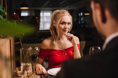 selective focus of attractive woman flirting with man in restaurant  clipart