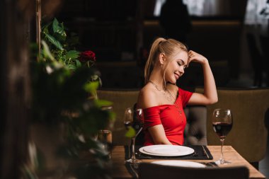 Kırmızı elbiseli restoranda oturan çekici sarışın kadın 