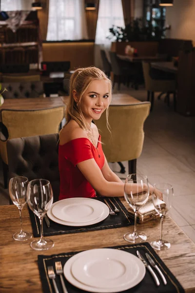Приваблива Жінка Червоній Сукні Сидить Ресторані Посміхається Камеру — стокове фото