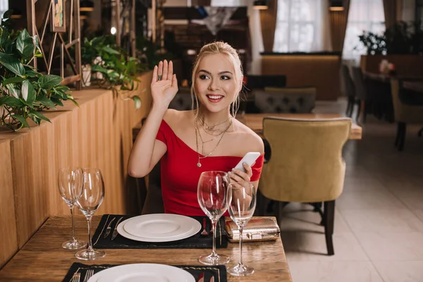 Aantrekkelijke Vrouw Rode Jurk Zittend Restaurant Zwaaien Hand — Stockfoto