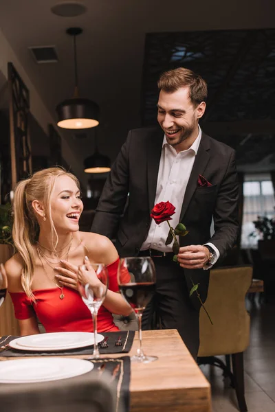 レストランでびっくりのガール フレンドに赤いバラを与える陽気な彼氏 — ストック写真