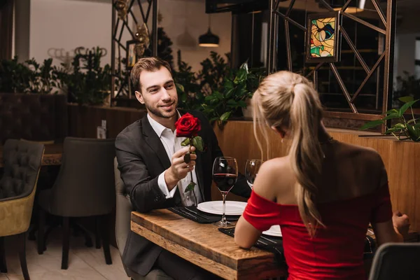 Schöner Freund Gibt Freundin Rote Rose Während Sie Restaurant Sitzt — Stockfoto