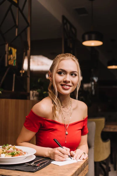 Attractive Blonde Woman Writing Paper Smiling Restaurant — Stock Photo, Image