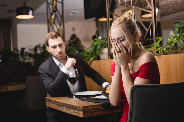 被冒犯的妇女在餐厅的男朋友附近哭泣的选择性焦点 — 图库照片
