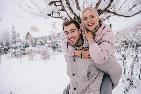 Lächelnder Mann Trägt Attraktive Blonde Frau Winter Auf Dem Rücken — Stockfoto