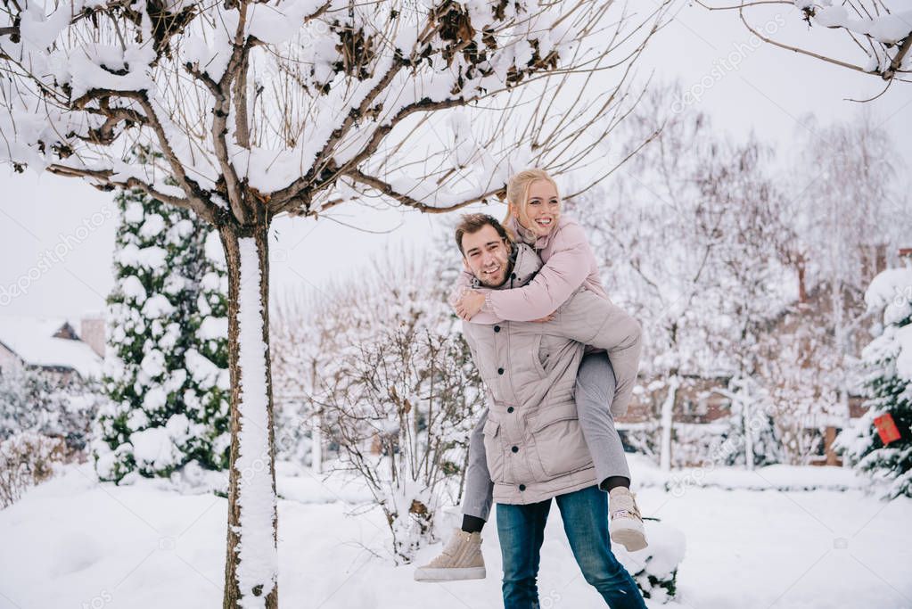playful couple spending time in snowy park 