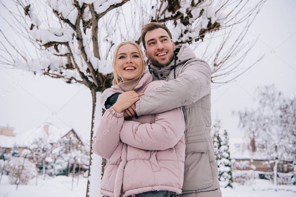 happy man and woman embrace each other in daytime in winter 