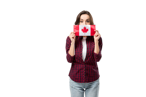 woman in casual clothes holding canadian flag in front of face isolated on white