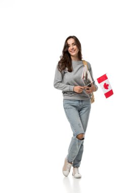 female student holding canadian flag and notebooks while looking at camera isolated on white clipart