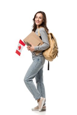 sırt çantası ve dizüstü bilgisayarlar üzerinde beyaz izole kamera bakarken Kanada bayrağı holding ile mutlu kız öğrenci
