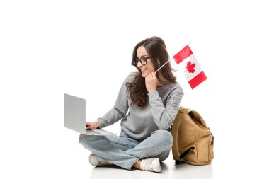 Kanada bayrağı ile oturan ve üzerinde beyaz izole dizüstü kullanarak kız öğrenci