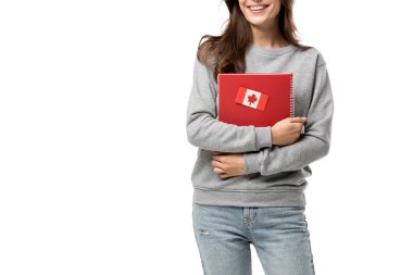 cropped view of female student holding red notebook with maple leaf sticker isolated on white clipart