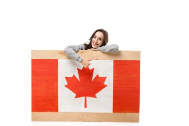 woman sitting behind wooden board with canadian flag and showing thumb up sign isolated on white clipart