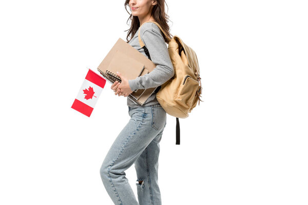cropped view of female student with backpack and notebooks holding canadian flag isolated on white